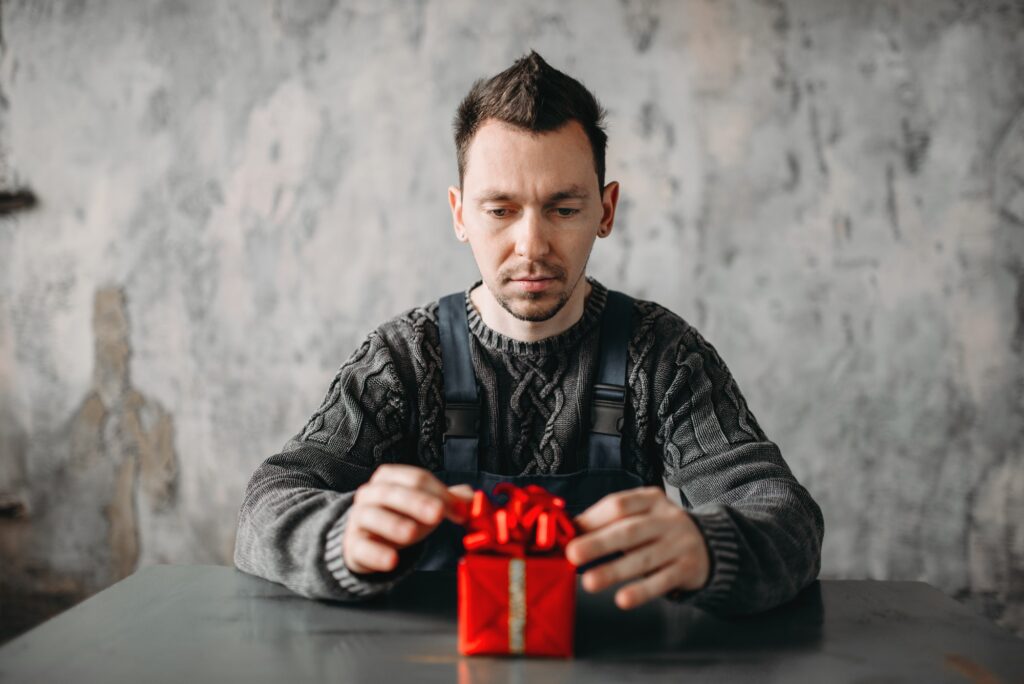 Autist man sitting against gift in wrapping paper